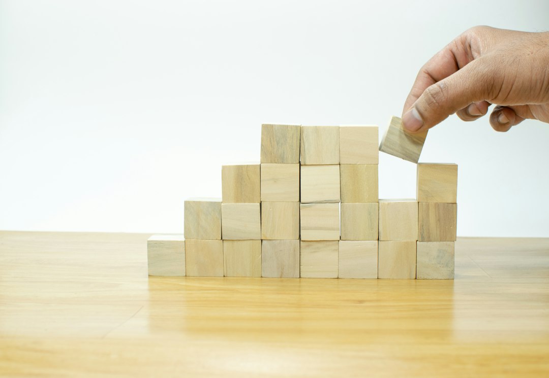 ADKAR Change Management Model Building Blocks Wooden blocks stacked in ascending steps, symbolising the ADKAR model's five sequential building blocks