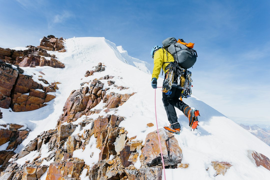 Climber reaching the summit ridge – adaptive leadership challenge Climber topping out on a mountain ridge, representing an adaptive leadership challenge
